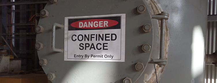 A paper permit binder beside a tablet showing a live confined space entry permit