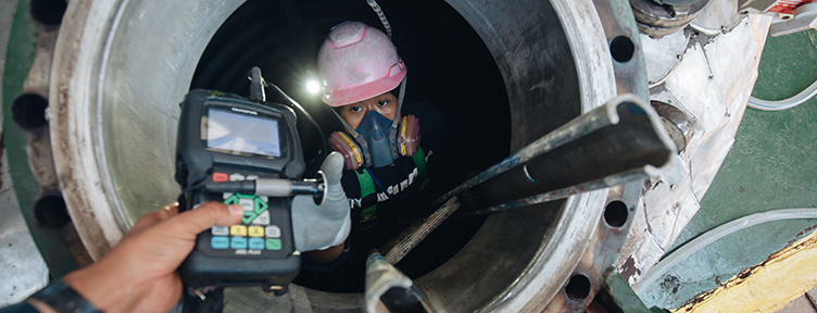 Confined space entry permit checklist on a clipboard beside a four-gas atmospheric monitor